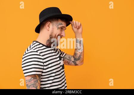 Smiling hipster man wearing stylish hat on orange background. Space for text Stock Photo