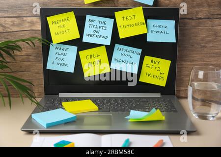 Many different reminder notes and laptop on table against wooden background Stock Photo
