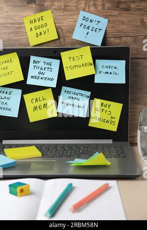 Many different reminder notes and laptop on table against wooden background Stock Photo