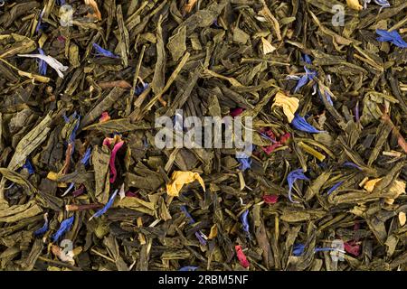 Flavoured green tea with rose petals and exotic fruits - mango, yellow peach and citrus fruits. Stock Photo