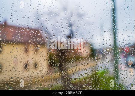 Water droplets on a window pane of an apartment building overlooking a farmhouse and a crossroads, Jena, Thuringia, Germany Stock Photo