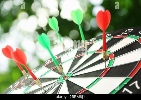 Dart board with color arrows hitting target outdoors Stock Photo