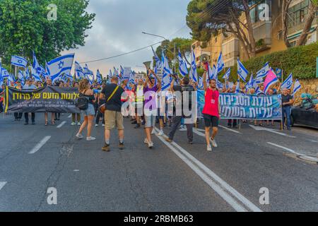 Haifa, Israel - July 08, 2023: People marching with flags and various signs. Week 27 of anti-government protest in Haifa, Israel Stock Photo