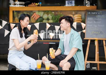 Cheerful couple eating street food when enjoying first date Stock Photo