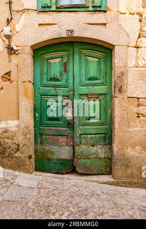 Ornate wooden double doors on the stone facade of a house on a cobbled street in Lamego, Portugal Stock Photo