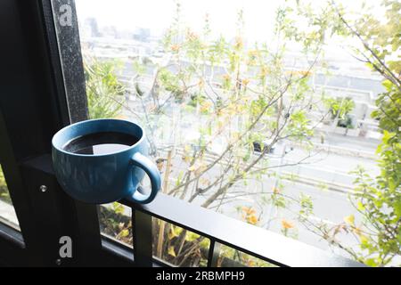 Coffee cup balanced an a balcony railing, with tree tops beyond. Home ...
