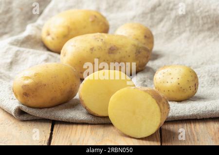 Ripe potato tuber cut in half on coarse burlap fabric. Close up. Stock Photo