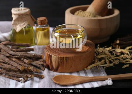 Dried sticks of licorice roots and essential oil on black table Stock Photo