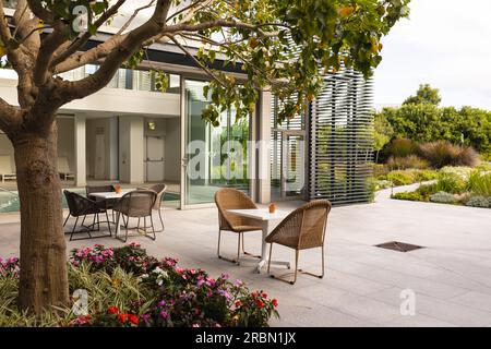 Empty chairs around table at patio outside modern hotel. Absence, unaltered, nature and architecture concept Stock Photo