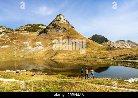 Three Austrian alphorn musicians named 'Klangholz' playing alphorn at lake Augstsee on mount Loser in Austria. Stock Photo