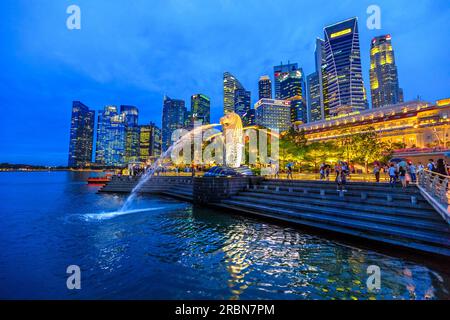 Singapore - April 27, 2018: night scenic Singapore touristic symbol at blue hour, the Merlion Statue in Merlion Park with luminous skyline of CBD Stock Photo