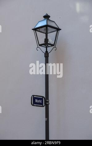 Old street lamp with street sign 'Zum Markt' in Frankfurt in front of white wall Stock Photo