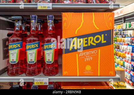Italy - July 10, 2023: Aperol bottles and box on shelf for sale in Italian supermarket. Aperol Italian aperitif liqueur for making spritz cocktails ma Stock Photo