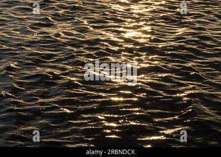 The sunset reflects it's golden light over waves of lake water during a summer evening. This was taken in Branson Missouri, United Stated at Table Roc Stock Photo