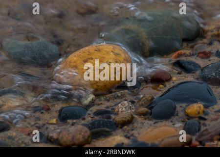 A capture of water flowing over some rocks along the Whitefish Point Bay in the Michigan, United States. Whitefish Point is located at the extreme sou Stock Photo