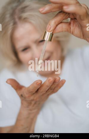 Crop anonymous female applying hyaluronic acid on her hand. Stock Photo