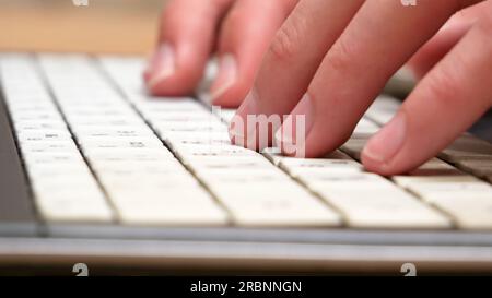 Hands, fingers fast typing on a white laptop keyboard, side view, computer keys extreme closeup, shallow dof. Man working on a netbook, chatting or me Stock Photo