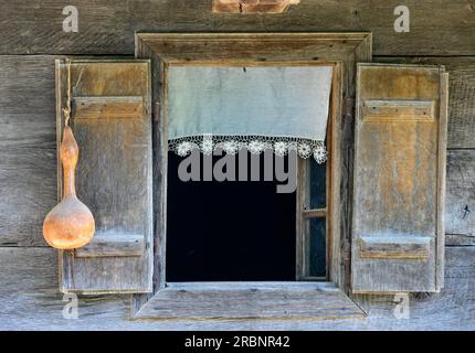 A window with lace curtain and gourd in an old wooden house in the village of Krapje. Lonjsko Polje Nature Park, Croatia. Stock Photo