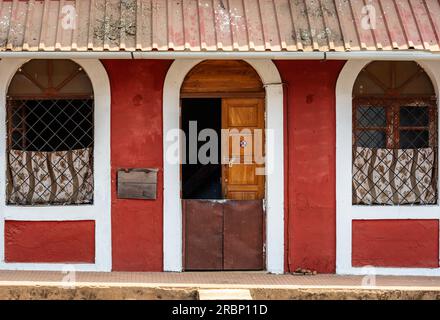 A telephoto image of the front of a red house with white arched door and window frames. Stock Photo