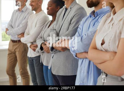Multiracial business team standing in row joining their hands Stock Photo