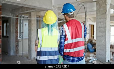 Man and woman builders standing backwards at construction site Stock Photo