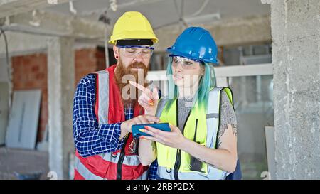 Man and woman builders using smartphone working at construction site Stock Photo