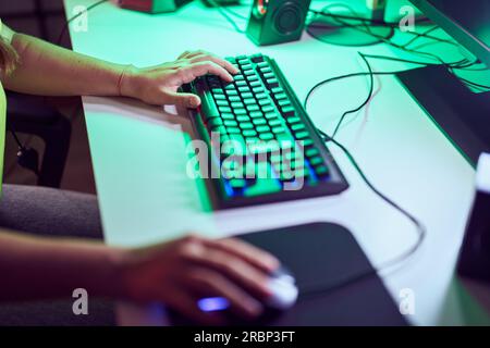 Young blonde woman using computer keyboard and mouse at gaming room Stock Photo