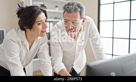 Senior man and woman business workers using computer working at office Stock Photo