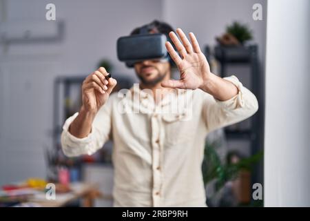 Young hispanic man artist using virtual reality glasses drawing at art studio Stock Photo