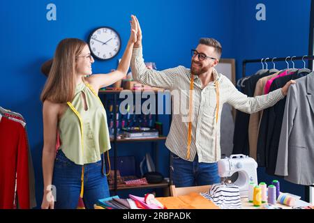 Man and woman tailors high five with hands raised up at clothing factory Stock Photo