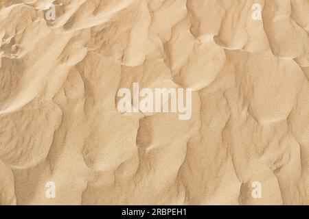 Natural sand texture. Yellow sand on the beach. Wavy sand background for summer designs. Stock Photo
