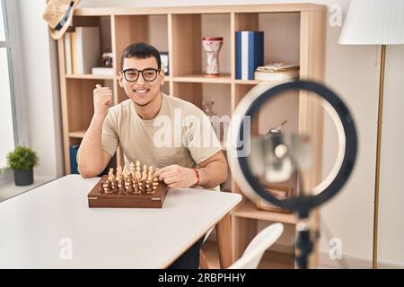 Young arab man doing chess tutorial pointing thumb up to the side smiling happy with open mouth Stock Photo