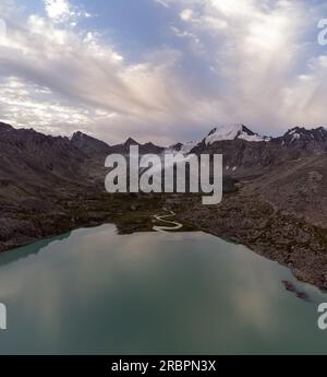 Immerse yourself in the breathtaking beauty of Kyrgyzstan's Ala-Kul lake, where serenity meets stunning mountain vistas. Nature's masterpiece! Stock Photo