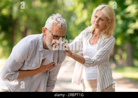 Senior man suffering from heart attack while walking with wife in park Stock Photo