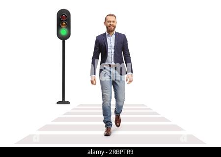 Full length portrait of a young smiling man crossing a street at green traffic light isolated on white background Stock Photo