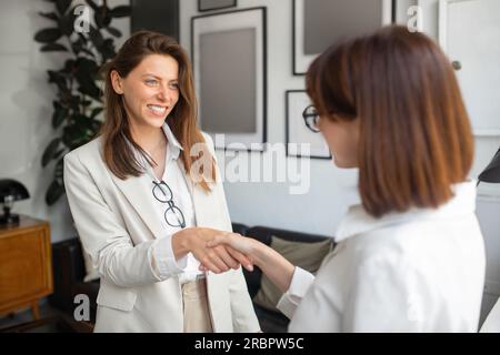 Two european businesswomen entrepreneurs shaking hands after discussing project, making agreement in office room Stock Photo