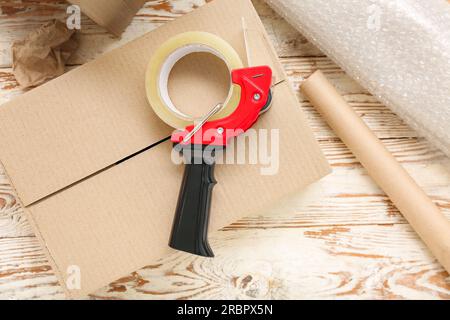 Packing tape dispenser, cardboard boxes and roll of bubble wrap on wooden background Stock Photo