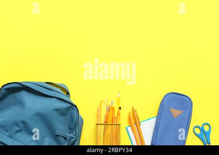 School backpack with stationery on yellow background Stock Photo