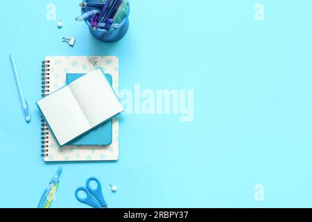 Composition with notebooks and different school stationery on blue background Stock Photo