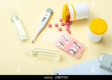 Thermometer, pillbox and ampules on yellow background Stock Photo