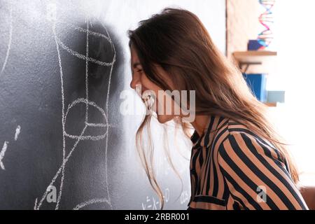 Angry female Math teacher near blackboard in classroom Stock Photo