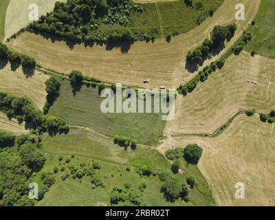 View from very height of green grass fields with hay bales and trees in the landscape Stock Photo