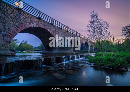 Old bridge over the Saale Jena-Burgau with small waterfall at sunset, Jena, Thuringia, Germany Stock Photo
