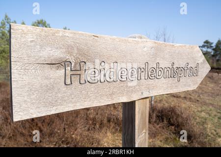 Wooden sign in the heathland with the inscription heath adventure trail in german language Stock Photo
