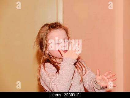 Girl is clapping. 5 years old. Funny and children concept. Add warm colors effect. Stock Photo