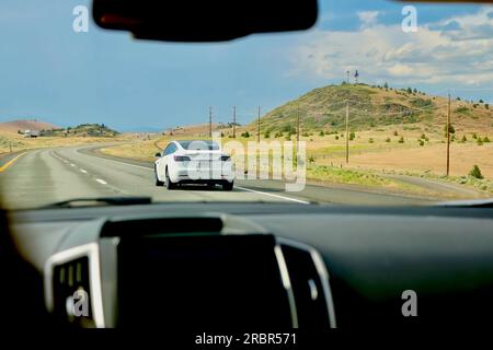 A white Tesla Model 3 driving north on Interstate 5 seen from inside a car California USA Stock Photo