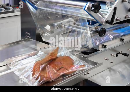 Linear food plastic tray package heat sealing machine. Food industry concept background Stock Photo