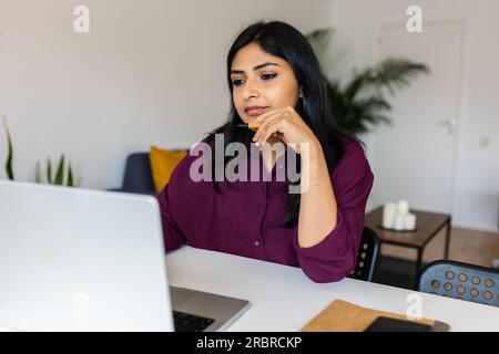Young indian woman working on laptop at home. Stock Photo