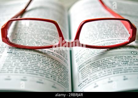 Red glasses lying on a dictionary Stock Photo