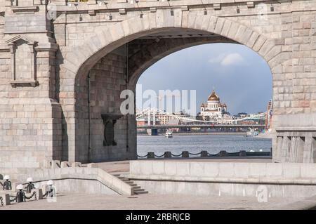 Cathedral of Christ the Saviour seen through the main arch of the Andreevsky railway bridge from the side of the Neskuchny garden in Moscow, Russian Stock Photo